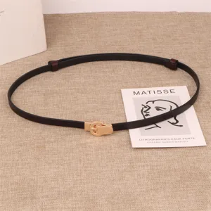 Details of the thin black leather belt featuring a chic gold metal double buckle design.