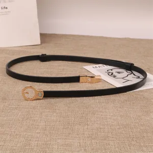 Detailed view of the slim black leather belt with gold metal interlocking buckle and fine loop.