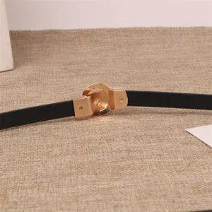 Close-up detail of a minimalist black thin leather belt featuring a chic gold interlocking buckle.