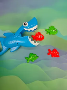 Close-up detail view of blue shark grabber toy and colorful fish for bath water play.