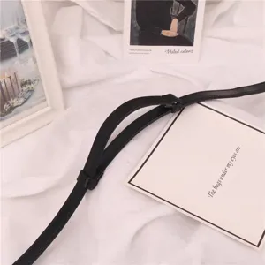 Detalle de cinturón fino negro, correa de cintura de cuero minimalista para mujeres, accesorio de vestido.