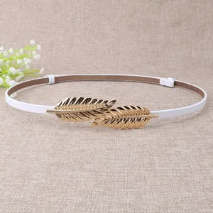 Close-up detail of stylish women thin white leather dress belt with golden leaf buckle accent.