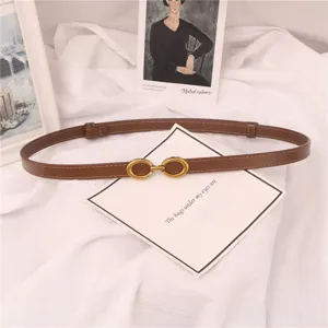 Cinturón fino marrón minimalista para mujer con hebilla dorada, detalle elegante sobre tela blanca.