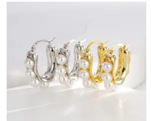 Primo piano di orecchini a cerchio a forma di U in oro e argento con piccole perle