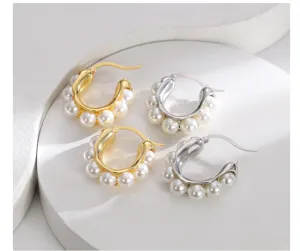 Primo piano di eleganti orecchini a forma di U color oro e argento con dettagli in perla
