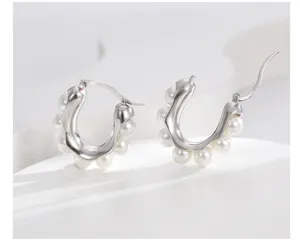Dettaglio di orecchini a cerchio a U in argento decorati con eleganti perle bianche