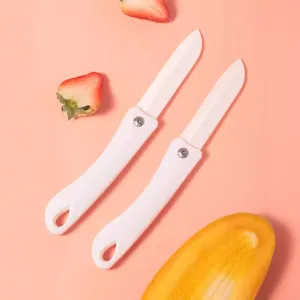 Deux couteaux pliables en céramique blanche présentés sur un fond rose propre