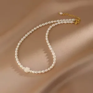 Primo piano di un'elegante collana di perle bianche con ciondolo a camelia in madreperla