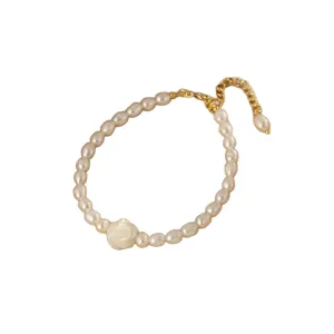 Elegante collana di perle con fiore di camelia bianca e catena d'oro regolabile.