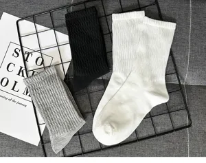Close-up detail view of black, white, and grey ribbed crew socks arranged neatly on grid.