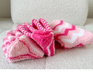 Close-up of pink and white striped fuzzy socks made from soft coral fleece for cozy winter wear.