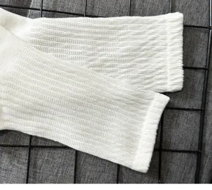 Close-up detail shot of white ribbed mid-calf socks showing soft knit texture clearly.