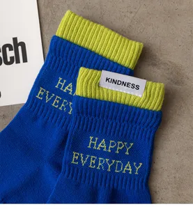 Close-up view of blue and lime green cotton crew socks featuring woven text and side label details.