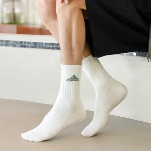 Men's white mid-tube cotton athletic socks featuring mountain embroidery, side angle view