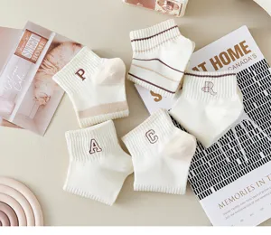 Close-up of cute white short socks featuring embroidered letter details and soft striped patterns.