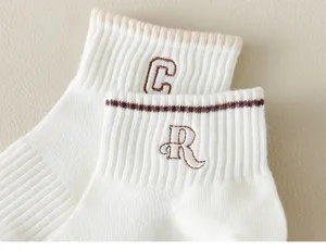 Close-up detail of white cotton short socks with cute embroidered letter cuffs design.