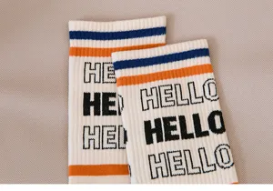 Détail en gros plan de chaussettes de sport bicolores pour hommes avec lettres Hello et bords.
