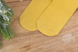 Gros plan de chaussettes en coton jaune douillet tricotées avec texture fine sur fond en bois.