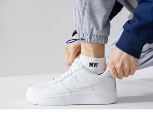 Toma detallada de calcetines cortos blancos transpirables para hombre con bordado negro.