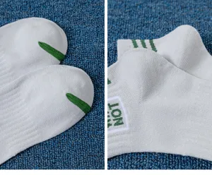 Detailed view of light gray men's ankle socks with green embroidered stripes and text.