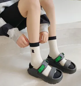 Gedetailleerde close-up van damessokken tot halverwege de kuit met borduurwerk en sandalen.