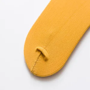 Close-up detail of mustard yellow ribbed velvet long socks texture and toe stitch.