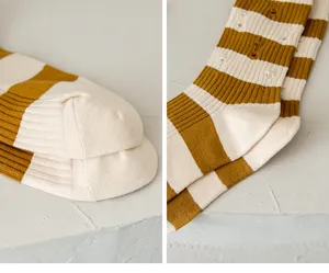 Close-up detail of women's yellow and white striped distressed knit mid-tube fashion socks.