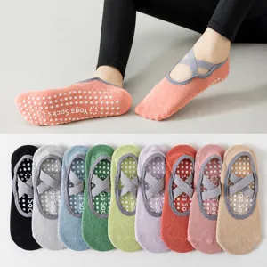 Anti-slip yoga socks for women with cross straps and grip soles for pilates and fitness workouts.