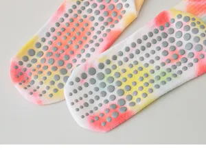 Close-up of colorful tie-dye yoga socks with grey non-slip grip dots on the sole for safety.