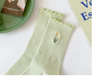 Women's light green ribbed mid-calf socks with delicate ruffle cuff and cute tulip embroidery.