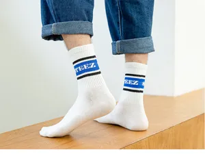 Close-up detail of trendy white crew socks featuring blue stripes and STEEZ knit letters.