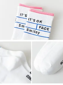 Détails en gros plan de chaussettes mi-hautes blanches en coton avec revers rose et texte.