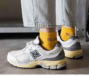 Detail shot of men's yellow cotton socks with letter print worn with sneakers on street style.