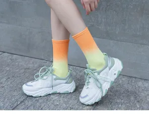 Detail shot of gradient dip-dye mid-tube socks paired with chunky sneakers in casual style.