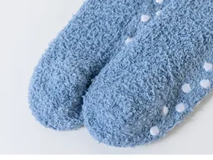 Close-up of blue fluffy coral fleece fuzzy socks showcasing white anti-slip sole dots.