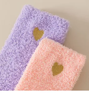 Detailed view of women's cozy coral fleece winter socks with gold embroidered heart pattern.