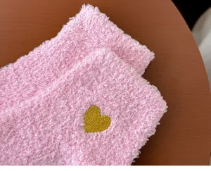 Cozy pink coral fleece sleep socks featuring cute gold heart embroidery for warm home lounging.