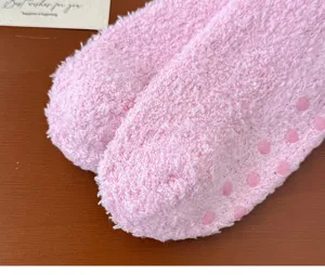 Pink fuzzy socks detail view, soft coral fleece material with anti-slip dots on sole.
