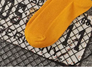Solid color yellow cotton mid-tube women socks with breathable ribbed knit design detail.