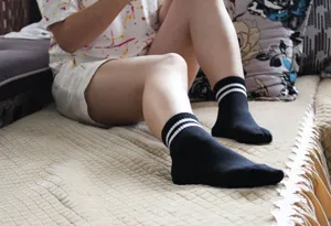 Calzini sportivi neri con doppie strisce bianche, modello casual da mezza altezza.