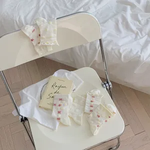 Cute Japanese style white mid-tube socks with sweet bows and strawberry patterns, detail view.