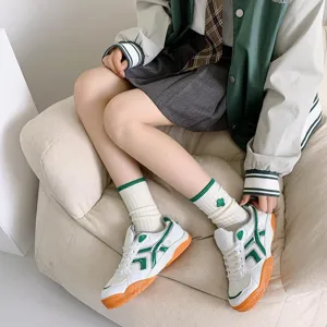 Close-up detail of stylish college white mid-tube socks with green stripes and clover embroidery.