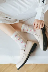 Close-up of sweet Japanese style sheer mid-tube socks featuring cute strawberry daisy and bow patterns.