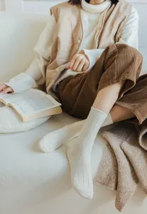 Close-up detail of women's ribbed white slouch socks in cozy winter lifestyle setting.