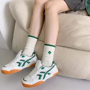 Detail shot of white mid-tube socks with green stripes and clover patch, cozy style.