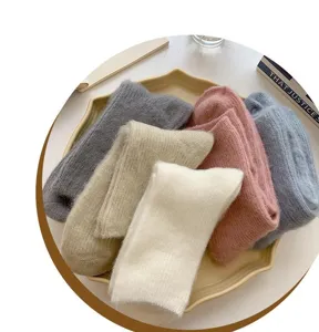 Close-up detail of cozy fluffy thick winter socks in assorted soft pastel colors on tray.