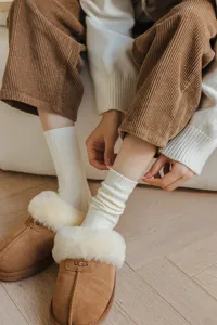 Detailed shot of cozy ribbed knit white socks paired with brown fuzzy slippers for winter styling.