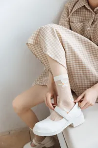 Nahaufnahme von transparenten weißen Kristallsocken mit zarten Gänseblümchen-Stickereien.