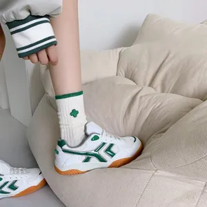 Detail shot of stylish green and white striped socks with clover embroidery and sneakers.