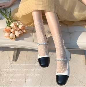 Primo piano dettagliato di calzini in rete trasparente con cuori abbinati a scarpe e fiori.